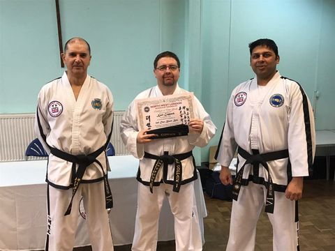 Karl holds his Second Dan certificate between instructors Keiron (left) and Dipesh (right)